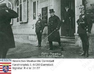 Hindenburg, Paul v. (1847-1934) / Porträt bei Besuch in Darmstadt, aus Hotel Traube herauskommend, mit polizeilichem Begleitschutz, Ganzfigur, Straßenszene