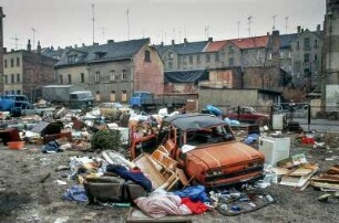Leipzig, März 1992. Sanierungsgebiet Lindenau. Schrott am Strassenrand, wilde Müllkippe, spielende Kinder