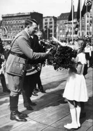 Ein Mädchen begrüßt Adolf Hitler mit einem Blumenstrauss