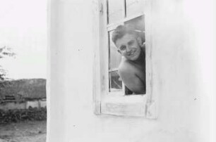 Zweiter Weltkrieg. Zur Einquartierung. Sowjetunion. Angehöriger der deutschen Wehrmacht, aus dem Fenster einer Bauernhütte schauend