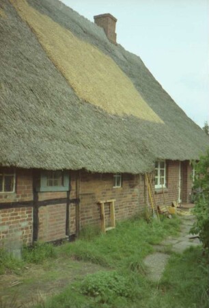 Klein Hansdorf: Am Wischhof 11: Bauernhaus mit Reetdach: Traufseite: Teilansicht: links Wirtschaftstrakt, rechts Wohntrakt mit Tür