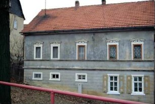 Hausfassade mit verzierten Fensterstürzen im OG