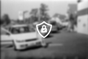 Autohaus Auto-Kraska: Am Weinberg: Kirschblütenfest: Parkplatz: Tochter [Name maskiert] auf Motorhaube von Mitsubishi Lancer, hinter Windschutzscheibe Preisschild: hinten Autos, Mann, Wimpelgirlande, Firmenschild, rechts an Fassade Firmenname