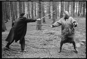 Mann und Frau fechten mit Stöckern im Wald