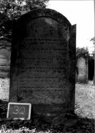Grabstein 32 (Index: 100107088) Material: Sandstein Zustand: verwittert Maße HxBxT: 129x72x13 cm Beschreibung: Stele, leicht eingezogener Rundbogenabschluß: Grabstein 32