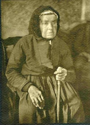 vgl. AIa034. Alte Dame sitzend mit Gehstock. Helle Aufnahme. Halbtotale