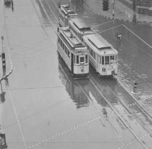Straßenszene an einer Kreuzung, Straßenbahn im Regen
