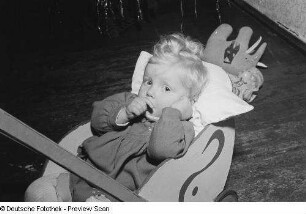 Porträt eines kleinen Mädchens mit Puppenwagen vor einem Weihnachtsbaum