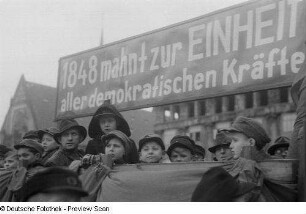 Kinder vor einem Propagandaplakat zu den Feierlichkeiten anläßlich der Revolution 1848