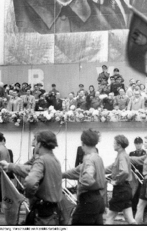 Berlin. 1. Deutschlandtreffen der Jugend. Erich Honecker (Vorsitzender der FDJ) am Mikrophon und Mitglieder der Staatsführung der DDR sowie internationale Gäste im Präsidium während der Friedensdemonstration, Pfingsten, 28. Mai 1950