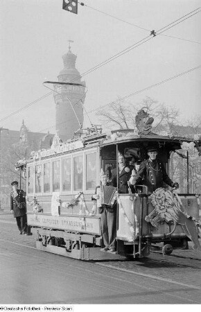 Musizierende Karnevalisten und Personal auf einer geschmückten Straßenbahn