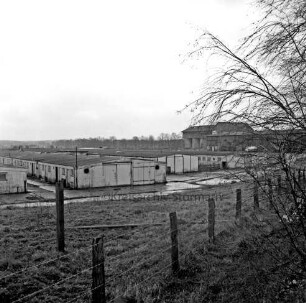 Heinrichshof, Gut: stillgelegte Schweinemastanlage: verfallene Schweineställe: im Hintergrund rechts Futtermittelgebäude: vorn Stacheldrahtzaun und Büsche
