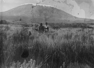 Landschaft mit Kibo : Blick über eine Ebene auf den verschneiten Kibo. In der Bildmitte zwei Männer, vermutlich Begleiter der Forschungsreisenden