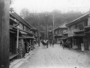 Blick zum 100-Stufen-Teehaus in Yokohama : Weltreisen. Japan. Yokohama. Straßenszene mit Rikschas in einer Ladenstraße. Blick zu den 100 Stufen des 100-Stufen-Teehauses auf dem Hügel