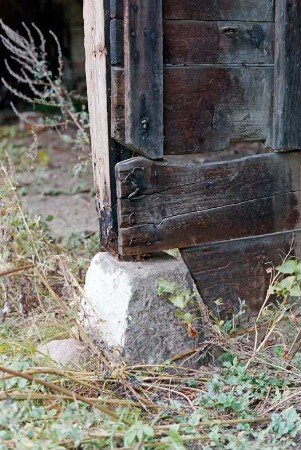 Gut Jersbek: Allee (3): Remise aus Fachwerk: Innenansicht, Detailaufnahme: Trennwand aus Holz auf Auflagestein