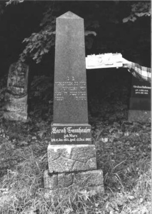 Grabstein 107 (Index: 100106441) Material: schwarzer Granit Zustand: gut Maße HxBxT: 197x40x28 cm Beschreibung: obeliskenartige Stele, getreppter Sockel, unterer Teil Rusticaimitat: Grabstein 107