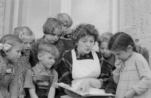 Eine Kindergärtnerin liest Kindern vor