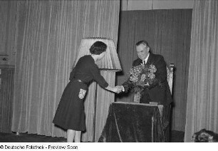 Hans Finohr bekommt von einer Frau auf der Bühne einen Blumenstrauß überreicht
