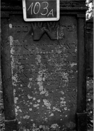 Grabstein 103 (Index: 100111213) Material: Sandstein Zustand: gut Maße HxBxT: 129x64x12 cm Beschreibung: ädikulaartige Stele mit Halbsäulen, giebelartiger Abschluß mit Verdachung Symbolik: segnende Hände, Blüte: Grabstein 103A