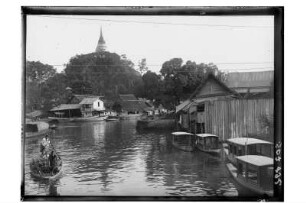 Kanal oder Fluss : Thailand. Blick über einen Khlong oder Fluss mit Booten gesäumt von Häusern auf eine Stupa