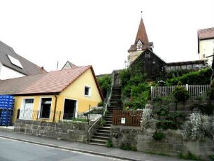 Ansicht von Norden mit Kirche (im Kern Gotisch) über Kirchhofmauer (Wehrgang im 18 Jh abgetragen) in erhöht liegendem Kirchhof aus dem Ort