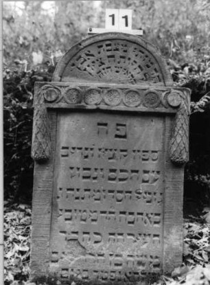 Grabstein 11 (Index: 100090919) Material: Sandstein Zustand: abgeblättert/Textverlust Maße HxBxT: 103x61x12 cm Beschreibung: Stele mit eingezogenem Rundbogen Symbolik: Girlande mit kreisförmigen Motiven: Grabstein 11