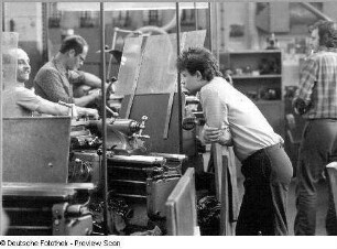 Arbeiter in einer Fabrik an einer Maschine während eines Gesprächs, aufgenommen in Dresden