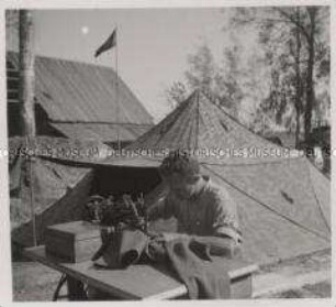 Wehrmachtssoldaten, Soldaten in Rußland, Kaum steht das Zeltlager der für kurze Zeit in Ruhe liegenden Einheit, wird auch die Nähmaschine ausgepackt und die beschädigte Ausrüstung wieder hergestellt.