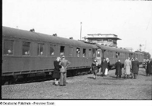 Deutschland. Bahnhof. Bahnsteig mit eingefahrenem Personenzug (mit Waggon 3. Klasse) und Reisenden
