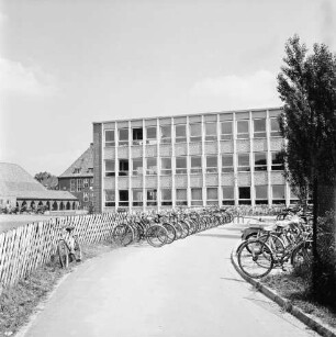 Sachsenwaldschule Gymnasium Reinbek: Schulstraße: Erweiterungsbau mit naturwissenschaftlichem Trakt: vorn Zuwegung mit Fahrradständern voller Fahrräder rechts und links: rechts Baum: links Jägerzaun: hinten links Altbau