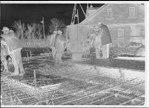 Staustufe Schweinfurt. Straßenbrücke. Betonieren des Überbaues auf dem Lehrgerüst zwischen Main und Saumain. Einbringen des Betons mit dem Kübel des Turmdrehkrans.