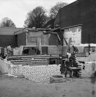 Tremsbüttel-Dorf: Gemeindezentrum: Mehrzweckhalle: Erweiterungsbau mit Bühne und Nebenräumen: Mitglieder der Freiwilligen Feuerwehr und des VfL Tremsbüttel von 1968 e.V. bei der Arbeit an Grundmauern: hinten rechts Gebäude