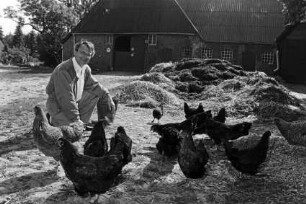 Hof von Günther Fielmann: Besitzer hockend neben Misthaufen und Hühnern: im Hintergrund Scheune