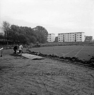 Stadion am Wendum: Erneuerung des Rasenplatzes: die städtische Gartenbaukolonne trägt den Rasen ab, im Hintergrund Wohngebäude