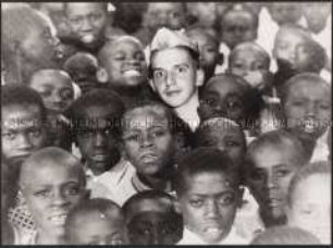 Gruppe von dunkelhäutigen Kindern mit reinmontiertem Gesicht eines hellhäutigen Jugendlichen (Prämiertes Foto Sonderthema: Anders leben)
