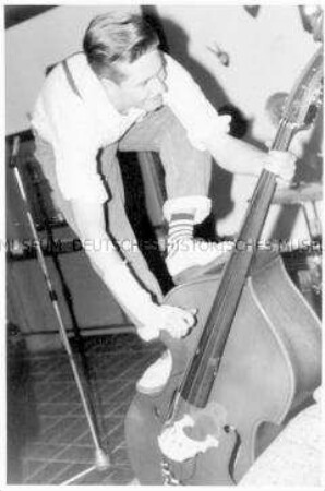 Bassist musiziert auf seinem Bass stehend (Altersgruppe 14-17)
