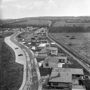 Im Hölk: Einfamilienwohnhäuser, dahinter die Eisenbahnstrecke Richtung Neumünster, im Hintergrund der Stadtforst Kneeden: Blick nach Westen