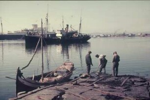 Reisefotos. Passagierschiff und Lastschiff. Ansicht vor einer Küste mit Fischer und Fischerboot an einem Steg