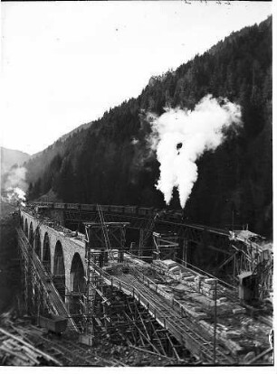 Arbeiten an der Fahrbahn des neuen Viaduktes und alter Viadukt mit einem darauf befindlichen Eisenbahnzug