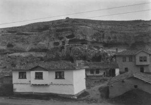 Dorf mit Höhlen : Blick auf Häuser in einem Dorf. Im Hintergrund eine Felswand mit Höhlen