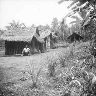 Hütte der Bubi : Aufnahme eines Mannes, der sich vor einer Hütte der Bubi auf Bioko befindet.