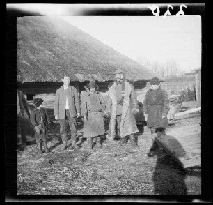 bei Dubischki (=Dubièiai (?), Litauen): 5 Einheimische vor einem reetgedeckten Holzhaus ("Russen bei Dubischki" bzw. "An der Komaika (=Kamaja/Kamoja, Gewässer in Litauen)")