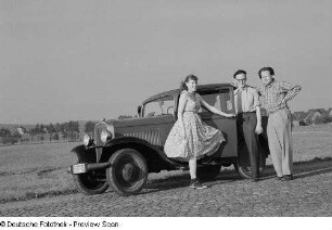 Das Ehepaar Rössing und ein Mann (Reiner) neben einem Opel 1,2