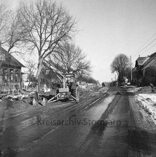 Straßenbau: Barghorster Straße: links Bagger und Baumaterial: hinten rechts und links Wohnhäuser und Bauernhäuser: Winter