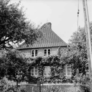 Bauernhaus von Heinz Lange: Giebelfront mit Rankgewächsen: davor Vorgarten mit Bäumen: vorn rechts Fahnenmast