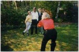 Rückenansicht eines Mannes, der im Garten Familienmitglieder fotografiert (Sonderthema: Familienbilder)
