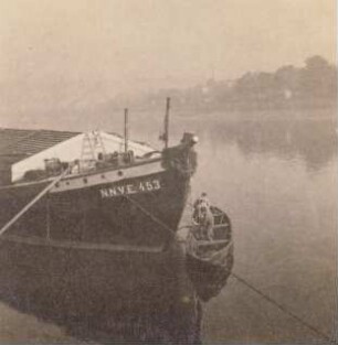Elbschiffer. Schiffer teeren vom Beiboot aus die Bordwände am Bug eines Schleppkahnes
