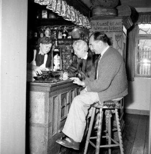 Ateliergasthaus. Gaststube. Paar an der Theke, auf Barhockern sitzend