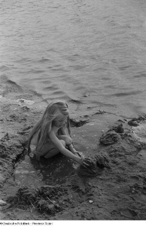 Mädchen, an einem Ufer mit Sand spielend