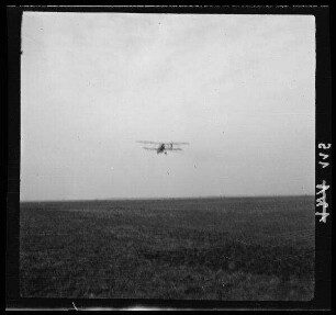 [Vitry-en-Artois (Dep. Pas-de-Calais, Frankreich):] Doppeldecker im Landeanflug (Distanzaufnahme)